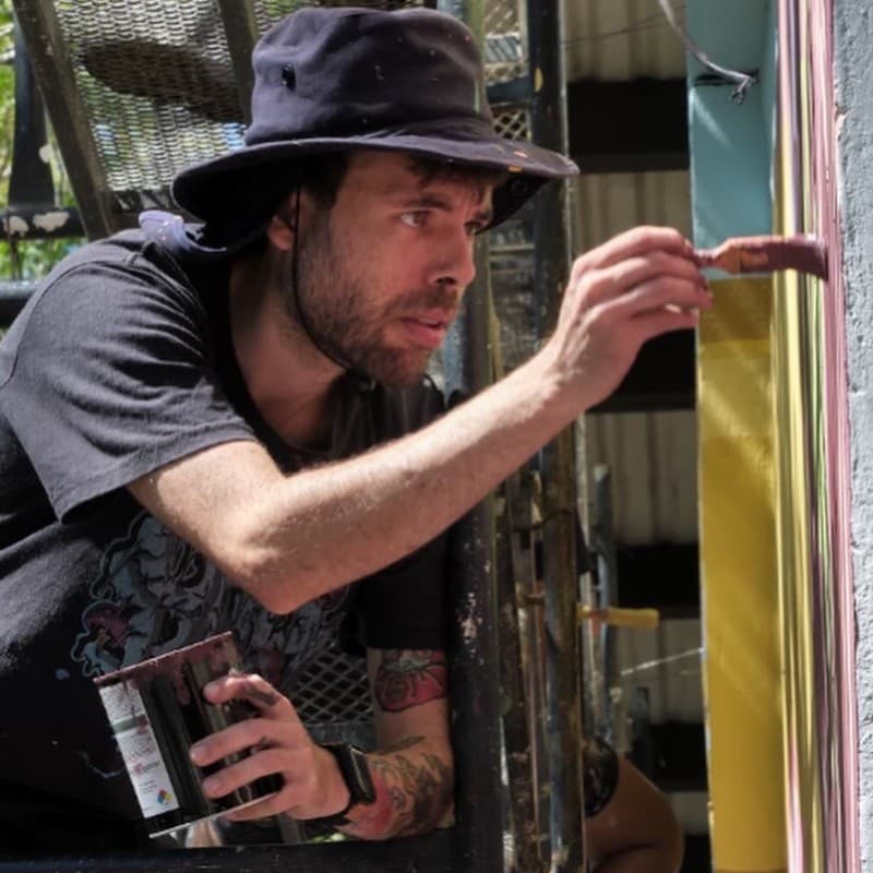 Gabriel Dumani pintando un mural desde una plataforma de trabajo